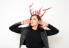 Deborah Frances-White, a woman with brunette hair, frames her face with her hands, palms facing us. She wears a big head-dress which reads "FEMINIST" Deborah Frances-White, a woman with brunette hair, frames her face with her hands, palms facing us. She wears a big head-dress which reads "FEMINIST"