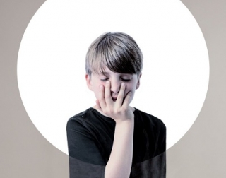 A young boy in a black shirt with his hand over his face A young boy in a black shirt with his hand over his face