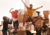 A man, woman and a group of children jump excitedly in the air in front of a pile of cardboard boxes. A man, woman and a group of children jump excitedly in the air in front of a pile of cardboard boxes.