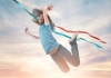 A girl flies joyously through the air, a sunset behind her and the strings of a kite trailing in the breeze behind her A girl flies joyously through the air, a sunset behind her and the strings of a kite trailing in the breeze behind her
