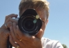 A woman with short blonde hair holds a dslr camera towards us A woman with short blonde hair holds a dslr camera towards us