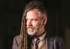 Duke Special, a man with a short beard and dreadlocks that fall on one side, wearing a suit and waistcoat Duke Special, a man with a short beard and dreadlocks that fall on one side, wearing a suit and waistcoat
