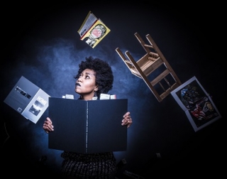 A woman holding a large book looks up a flying objects, such as a chair and other books A woman holding a large book looks up a flying objects, such as a chair and other books