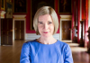 Lucy Worsley,a woman with short blonde hair and wearing a blue dress, stood in a historic stately home Lucy Worsley,a woman with short blonde hair and wearing a blue dress, stood in a historic stately home