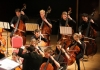 Students, as part of a larger orchestra, play a variety of string instruments Students, as part of a larger orchestra, play a variety of string instruments