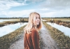 Kitty Mcfarlane, a young woman with medium length blonde hair, on a deserted marsh, looking back at the camera Kitty Mcfarlane, a young woman with medium length blonde hair, on a deserted marsh, looking back at the camera