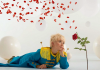 The Little Prince, dressed in a blue uniform, lays on a white floor and gazes at a rose which is drifting petals into the breeze The Little Prince, dressed in a blue uniform, lays on a white floor and gazes at a rose which is drifting petals into the breeze