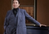 Jools Holland wears a blue suit and stands in front of a piano. Jools Holland wears a blue suit and stands in front of a piano.