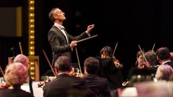 Alexander Shelley, a man in white tie attire, conducts an orchestra Alexander Shelley, a man in white tie attire, conducts an orchestra