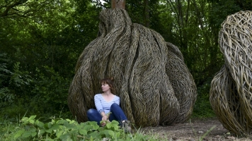 Laura Ellen Bacon sits in front of her sculpture, which is made of willow and wraps around a tree Laura Ellen Bacon sits in front of her sculpture, which is made of willow and wraps around a tree
