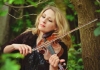 A blonde woman plays the violin in a forest A blonde woman plays the violin in a forest
