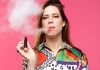 Lou Sanders, a young woman with long brown hair in a colourful print shirt, smokes a cigar Lou Sanders, a young woman with long brown hair in a colourful print shirt, smokes a cigar