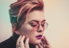 A woman with short hair looks down and touches her face A woman with short hair looks down and touches her face