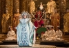 A princess in an opulent blue gown and headdress stands in front of a beautiful oriental court A princess in an opulent blue gown and headdress stands in front of a beautiful oriental court