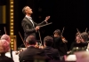 A conductor in a black jacket and a white bow tie leads an orchestra A conductor in a black jacket and a white bow tie leads an orchestra
