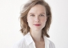 A woman with light brown hair wearing a white shirt smiles at the camera A woman with light brown hair wearing a white shirt smiles at the camera