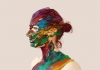 A woman in profile. Her face, neck and chest has been covered with streaks of multi-coloured paint. A woman in profile. Her face, neck and chest has been covered with streaks of multi-coloured paint.