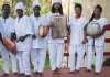 A group of musicians in white robes look at camera A group of musicians in white robes look at camera