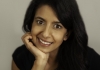 A woman leans on her hand and smiles at the camera A woman leans on her hand and smiles at the camera