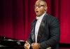 A man in a tuxedo singing in front of a piano A man in a tuxedo singing in front of a piano