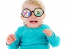 A baby with blonde hair wears a green jumper and a pair of multi-coloured glasses A baby with blonde hair wears a green jumper and a pair of multi-coloured glasses