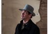 A man in a black jacket and a grey hat looks up and to the left A man in a black jacket and a grey hat looks up and to the left