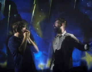 Two musicians in front of an abstract blue background. Two musicians in front of an abstract blue background.