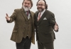 Two bearded men in suits hold stand together and smile at the camera Two bearded men in suits hold stand together and smile at the camera