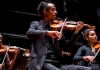 A man in concert dress sat playing the violin A man in concert dress sat playing the violin