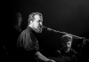 A black and white image of John Grant onstage. A black and white image of John Grant onstage.