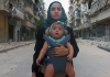 A photo of a woman carrying her baby set against the rubble and ruins of Aleppo A photo of a woman carrying her baby set against the rubble and ruins of Aleppo