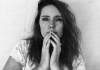 Black and white. A woman with long hair looks at the camera. Her hands are in front of her face. Black and white. A woman with long hair looks at the camera. Her hands are in front of her face.