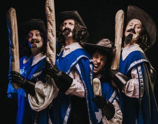 Four men with curly hair in blue coats, stood looking sideways at the camera and holding french baguettes. Four men with curly hair in blue coats, stood looking sideways at the camera and holding french baguettes.