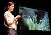 A woman looking down at a device with a screen with green earth in the background A woman looking down at a device with a screen with green earth in the background