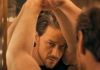 A man in a black t-shirt leaning on a mirror and looking at his reflection. A man in a black t-shirt leaning on a mirror and looking at his reflection.