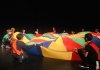 A group of children kneel around a brightly coloured piece of fabric on the floor A group of children kneel around a brightly coloured piece of fabric on the floor