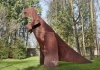 A sculpture of a dinosaur in a field A sculpture of a dinosaur in a field