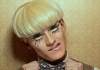 A man with blonde hair and drag make up tilts his head to the right, looking straight at the camera. A man with blonde hair and drag make up tilts his head to the right, looking straight at the camera.