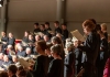 A choir stands in rows, looking at sheet music. A choir stands in rows, looking at sheet music.