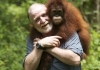 A man carrying an orangutan round his shoulders in the rainforest A man carrying an orangutan round his shoulders in the rainforest