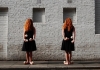 Two girls with red hair over their face wear dresses and juggle Two girls with red hair over their face wear dresses and juggle