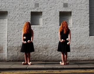 Two girls with red hair over their face wear dresses and juggle Two girls with red hair over their face wear dresses and juggle