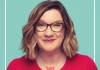 Comedian Sara Millican wearing glasses and a red jumper on a green background Comedian Sara Millican wearing glasses and a red jumper on a green background