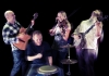 Urban Folk Quartet laughing and playing the drums, guitar, mandolin and fiddle Urban Folk Quartet laughing and playing the drums, guitar, mandolin and fiddle