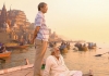 Two men stand on a boat looking out with more boats and ancient buildings behind them. Two men stand on a boat looking out with more boats and ancient buildings behind them.
