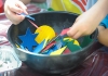 A child's hands playing with craft materials in a bowl A child's hands playing with craft materials in a bowl