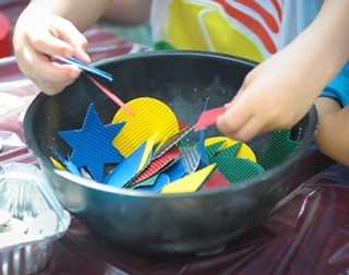 A child's hands playing with craft materials in a bowl A child's hands playing with craft materials in a bowl
