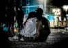 A boy and a girl wearing modern clothes, sitting in the middle of a a dark street A boy and a girl wearing modern clothes, sitting in the middle of a a dark street