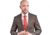 Comedian Tom Allen wearing a grey suit on a white background Comedian Tom Allen wearing a grey suit on a white background