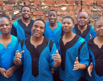 Singers wearing blue and black togas, standing in front of a brick wall Singers wearing blue and black togas, standing in front of a brick wall
